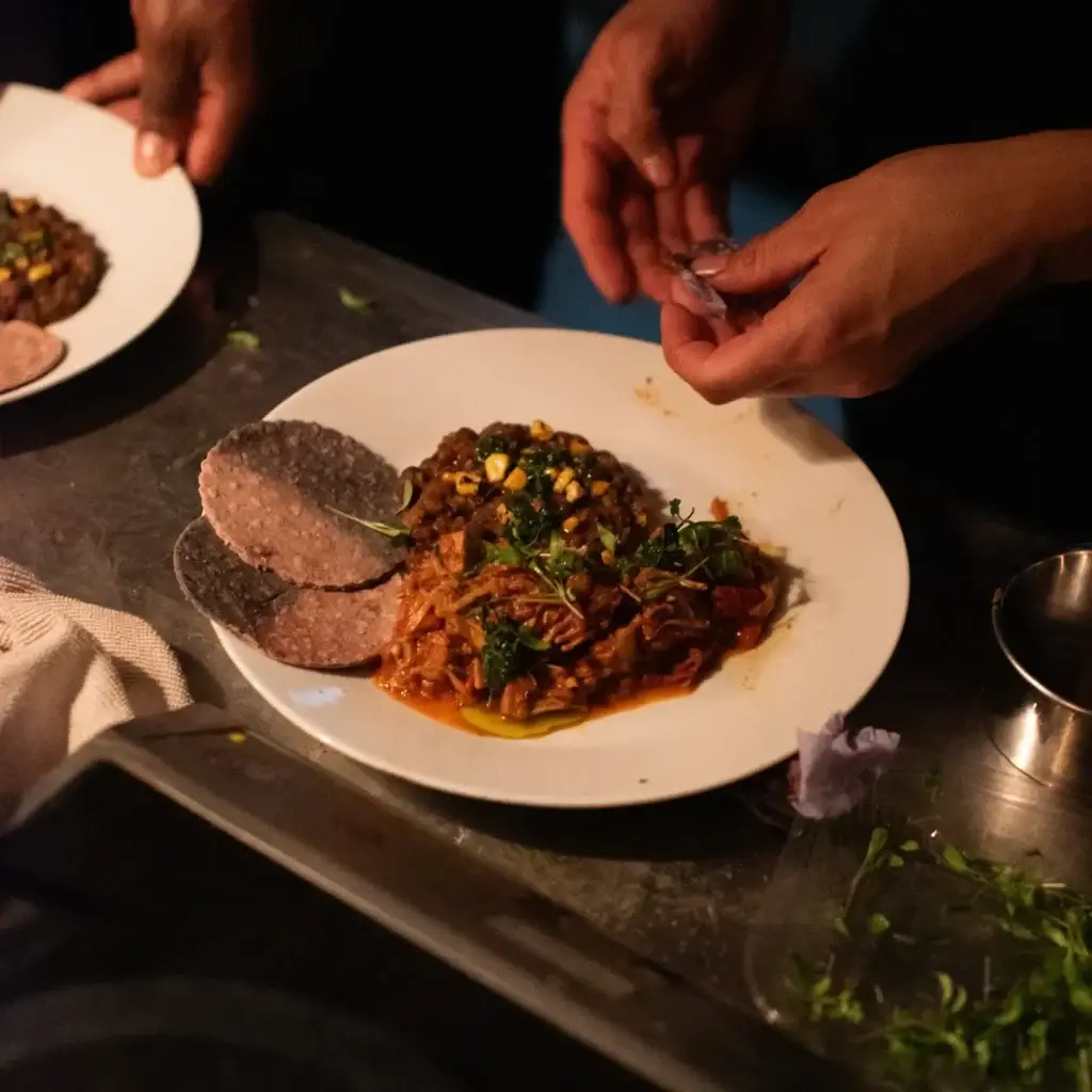 Chef’s hands adding the finishing touches to a plated dish.