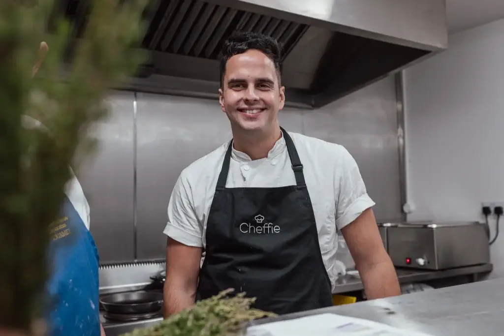 Chef Nick Rapson smiling in a professional kitchen.